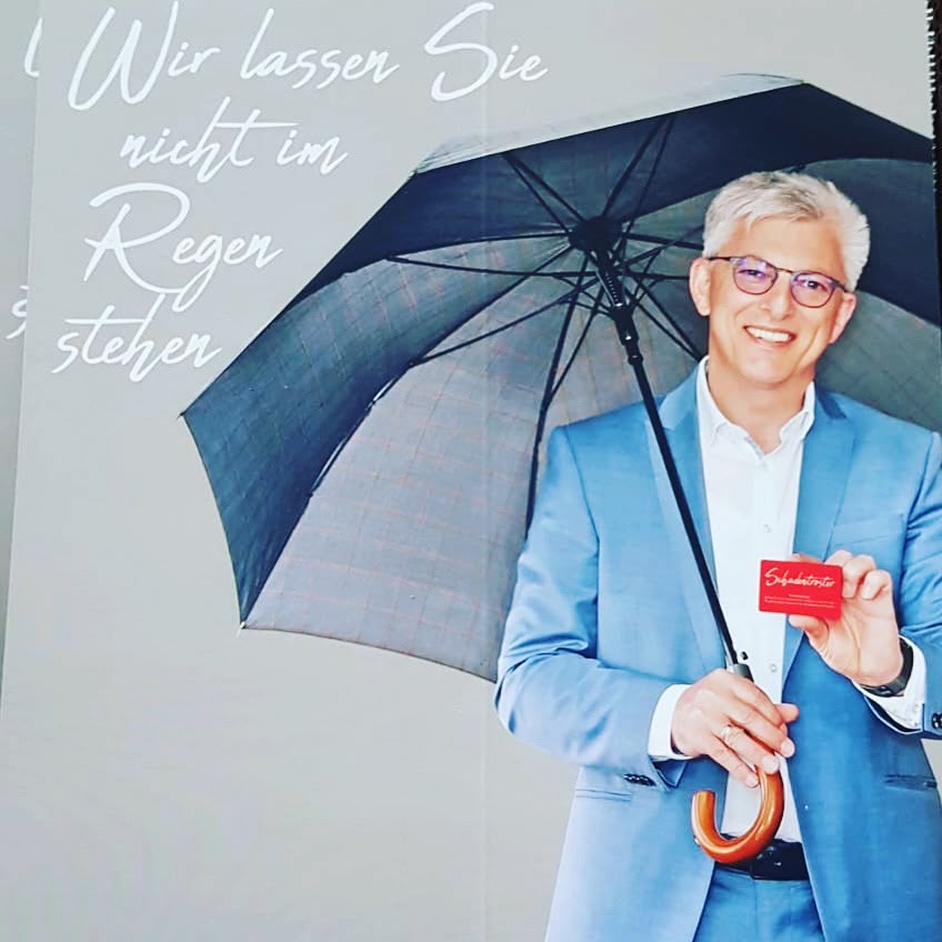 Joachim Lebherz mit Regenschirm und Schadentreter-Karte – Wir lassen Sie nicht im Regen stehen